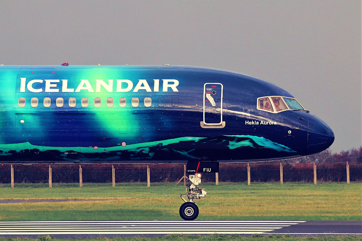 Icelandair plane decorated with northern lights on runway.